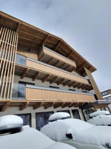 a building with snow covered cars in front of it at Pension Norika in Saalbach-Hinterglemm