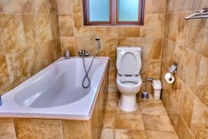 a bathroom with a bath tub and a toilet at Potato Suites n Spa in Gaborone