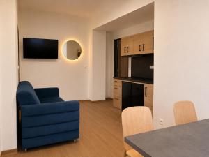 a living room with a blue chair and a kitchen at Pension Klatovy in Klatovy