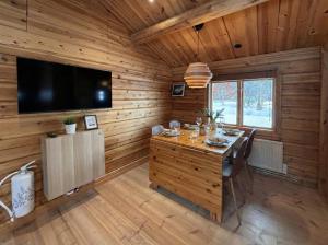 a dining room with a table and a flat screen tv at Charmig timmerstuga i Vemdalen in Vemhån
