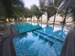 a large swimming pool with blue water and palm trees at Greenway Retreat Resort in Puducherry Airpoert