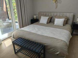 a bedroom with a large bed with a blue bench at Huize Zondag in Beneden-Leeuwen