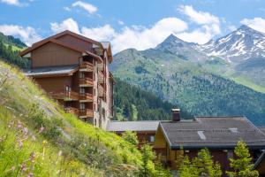a building on a hill with mountains in the background at Résidence Pierre & Vacances Les Sentiers du Tueda in Méribel