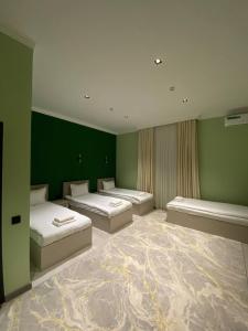 a room with three beds and green walls at Pandora Hotel in Samarkand