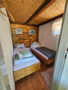two beds in a small room with wooden walls at Country House Speedy in Komiža