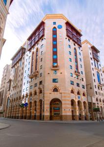 a large brick building with blue windows on a street at Jiwar Al Madina Hotel in Medina