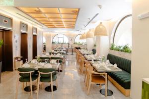 a restaurant with long tables and green chairs at Jiwar Al Madina Hotel in Medina