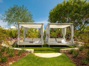a couple of white beds in a garden at Hyatt Regency Vilamoura Algarve in Vilamoura
