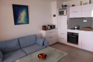 a living room with a blue couch and a kitchen at Plage de Miramar in Théoule-sur-Mer
