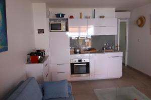 a small kitchen with white cabinets and a blue couch at Plage de Miramar in Théoule-sur-Mer