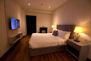 a hotel room with a bed and a television at The Address Boutique Hotel Karachi in Karachi +13 photos