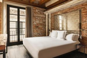 a white bed in a room with a brick wall at Aparthotel Arai 4* Superior in Barcelona +37 photos