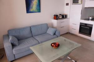a living room with a blue couch and a glass table at Plage de Miramar in Théoule-sur-Mer