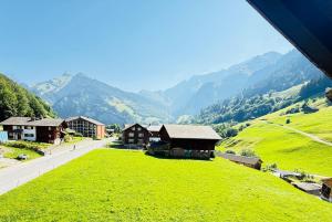 a green hill with houses and mountains in the background at Sternen B&B & Ristorante in Elm