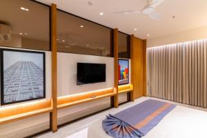 a living room with a tv and a large window at Lords Inn Sanand in Chharodi