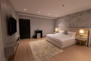 a bedroom with a white bed and a television at The Address Boutique Hotel Karachi in Karachi