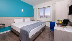 a hotel room with a bed and a desk with a laptop at Transamerica Executive Belo Horizonte in Belo Horizonte