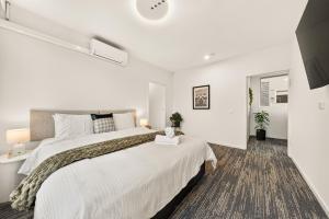 a white bedroom with a large bed and a window at Canvas On Barkly Apartments St Kilda in Melbourne