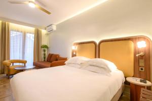 a bedroom with a large white bed and a living room at Hôtel Rotonde Aix-en-Provence centre in Aix-en-Provence