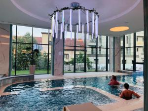two people sitting in a swimming pool in a building at Grand Hotel President in Baile Felix