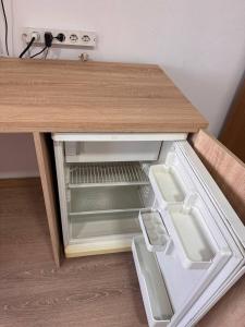 an open drawer in a wooden table with an empty refrigerator at Very good location in Hunedoara