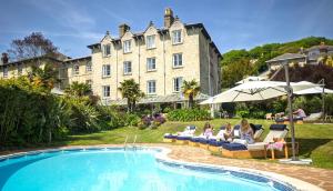 a group of people sitting on lounge chairs next to a pool at The Royal Hotel in Ventnor