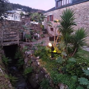 a stone building with a bridge over a creek at Rego de Cora By Oktheway in Valcarría