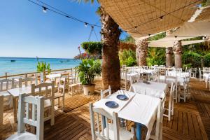a restaurant with white tables and chairs on the beach at Kampaoh Tossa de Mar in Tossa de Mar