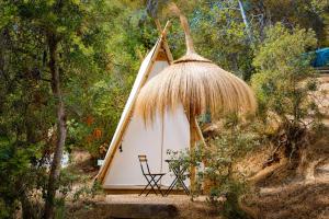 a small tent with a chair and a straw roof at Kampaoh Tossa de Mar in Tossa de Mar