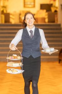 a woman holding a tray of food with a plate of food at The Royal Hotel in Ventnor