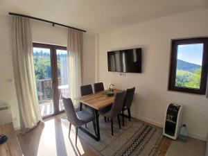 a dining room table with chairs and a television on the wall at Vila Golijat in Raška