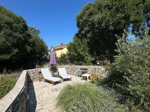 two chairs and an umbrella on a stone patio at Apartments Mester in Sveti Anton +1 photo