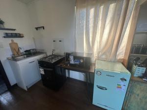 a kitchen with a stove and a sink and a refrigerator at Quincho la Beli in Chillán