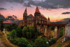 a castle on a hill with a sunset in the background at Hunyadi Nest in Hunedoara