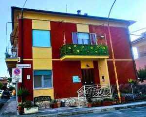 a red and yellow building with a balcony on a street at Casa Elvezia Guest House in SantʼElpidio a Mare