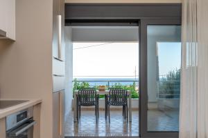 a kitchen with a table with chairs and a view of the ocean at Anemi Residence in Chios