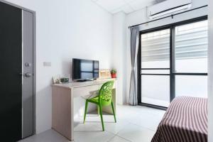a room with a desk with a television and a green chair at 雅居旅店 in Puli