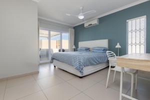 a blue bedroom with a bed and a table at Vallen Lodge 2 in Ballito