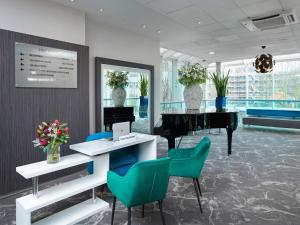 a room with a piano and chairs and a table at Novotel London West in London