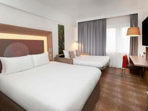 a hotel room with two beds and a desk at Novotel London West in London +84 photos