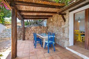 a patio with a table and chairs and a stone wall at Villa Sardinia Costa Smeralda in Arzachena