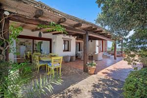 a patio with a table and chairs under a wooden pergola at Villa Sardinia Costa Smeralda in Arzachena