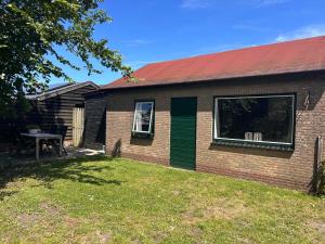 a brick house with a red roof and a yard at Bungalow Halfweg in Ballum