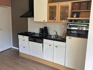 a kitchen with white cabinets and a black counter top at Bungalow Halfweg in Ballum