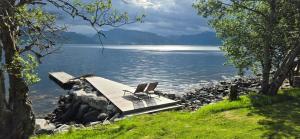 zwei Stühle stehen auf einem Steg an einem Gewässer in der Unterkunft Tiny house with Fjordview! in Lauvstad