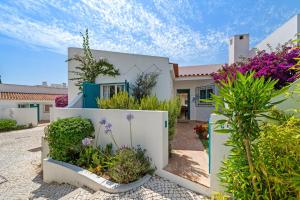 a white house with plants in front of it at Prainha Alvor - Cozy Villa in Alvor