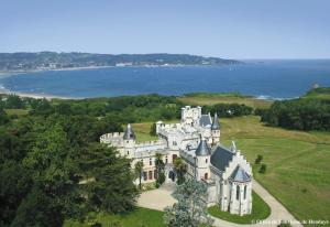 an old castle on a hill with the ocean in the background at Résidence Mer & Golf Sokoburu in Hendaye