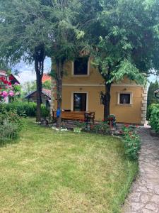 a yellow house with a bench in the yard at Vila Damjanka Banja Vrujci in Popadić