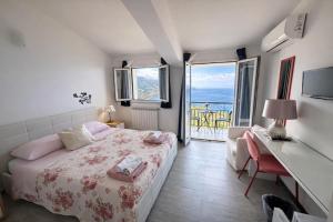 a bedroom with a bed and a desk and a balcony at Blue Sky House in Taormina