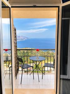 a balcony with a table and chairs and the ocean at Blue Sky House in Taormina